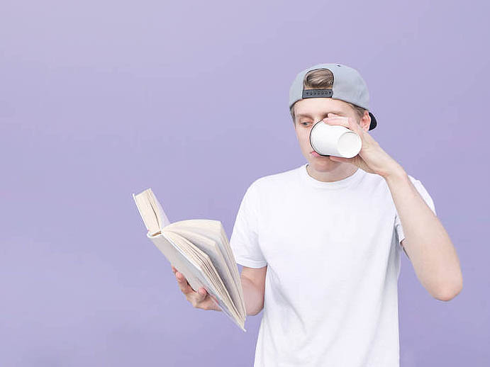 Portrait of a young man in a cap and a white T-shirt who reads a
