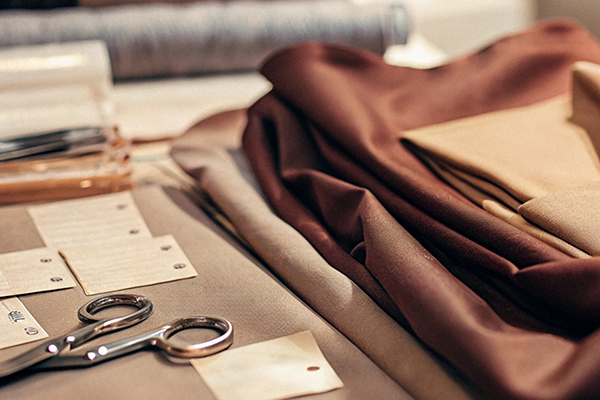 Folded fabrics in earthy tones, scissors, and fabric tags arranged neatly on a designer's workspace.