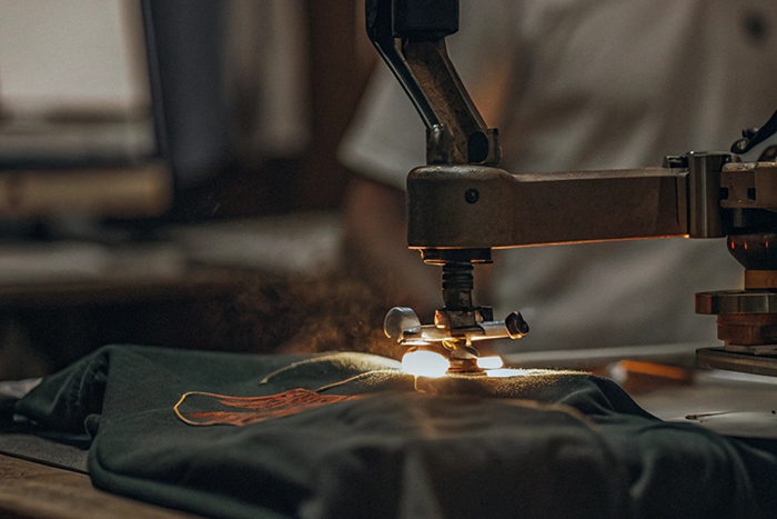 Close-up of a heat press machine printing a logo onto a dark-colored garment.