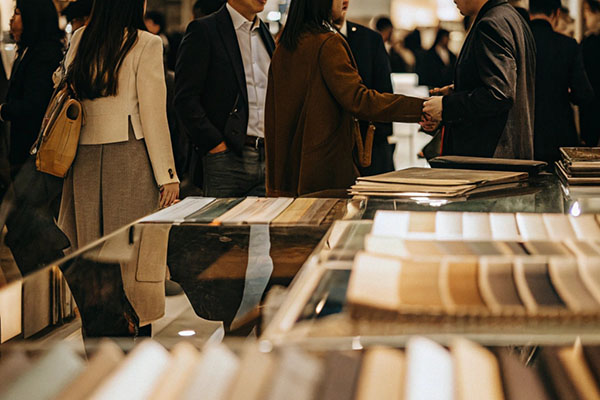 Professionals interacting in a fabric and materials showroom, with swatches displayed on glass counters.