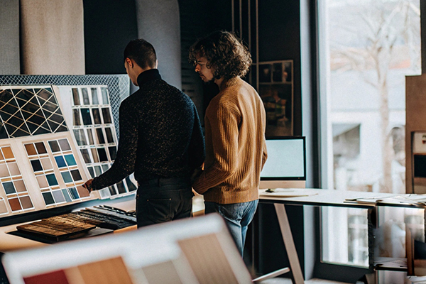 Two designers examining fabric samples and patterns in a creative studio with natural light and modern decor.