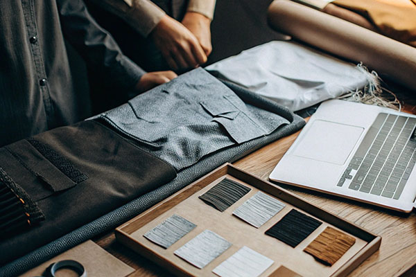 Designers arranging fabric samples and swatches next to a laptop on a wooden table.