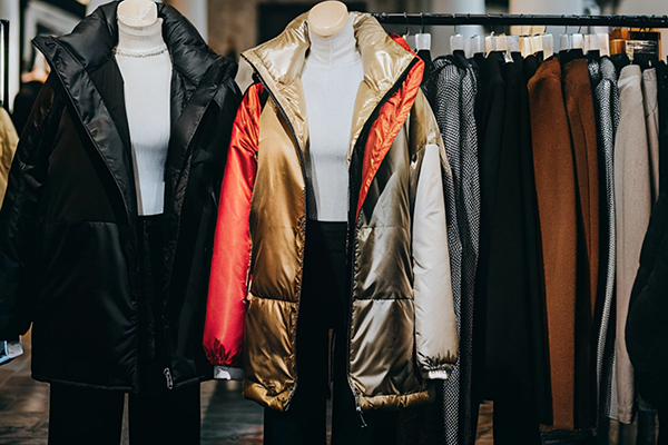 Mannequins wearing puffer jackets and racks of stylish clothing in an American fashion boutique.