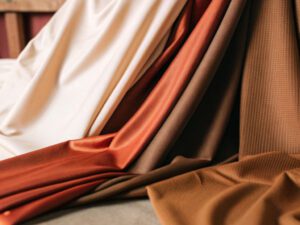 Close-up of polyester and spandex fabric draped in shades of cream, orange, and brown.