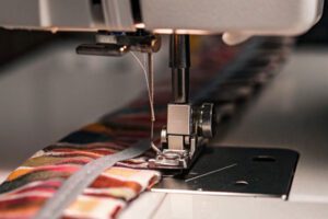 Close-up of a sewing machine stitching colorful fabric with precise detailing.