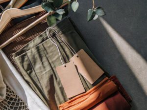 Close-up of eco-friendly fabrics in earthy tones with blank tags and wooden hangers, promoting sustainability in fashion.