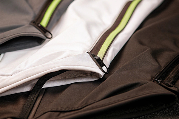 Close-up of activewear pants featuring contrasting zippers and green accents for a sporty design.