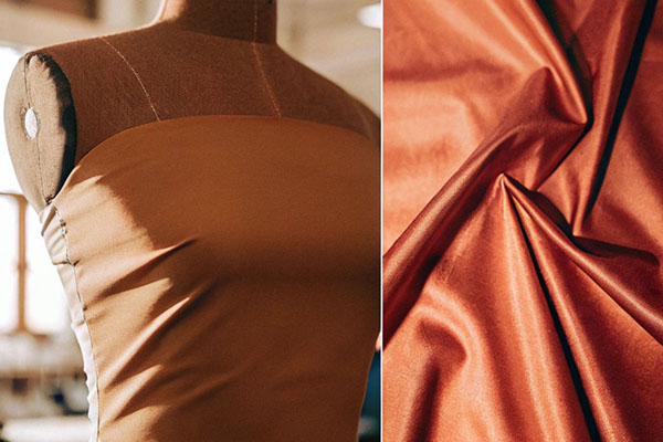 A mannequin draped with burnt orange satin fabric on the left and a close-up of the smooth, shiny material on the right, illuminated by warm light.
