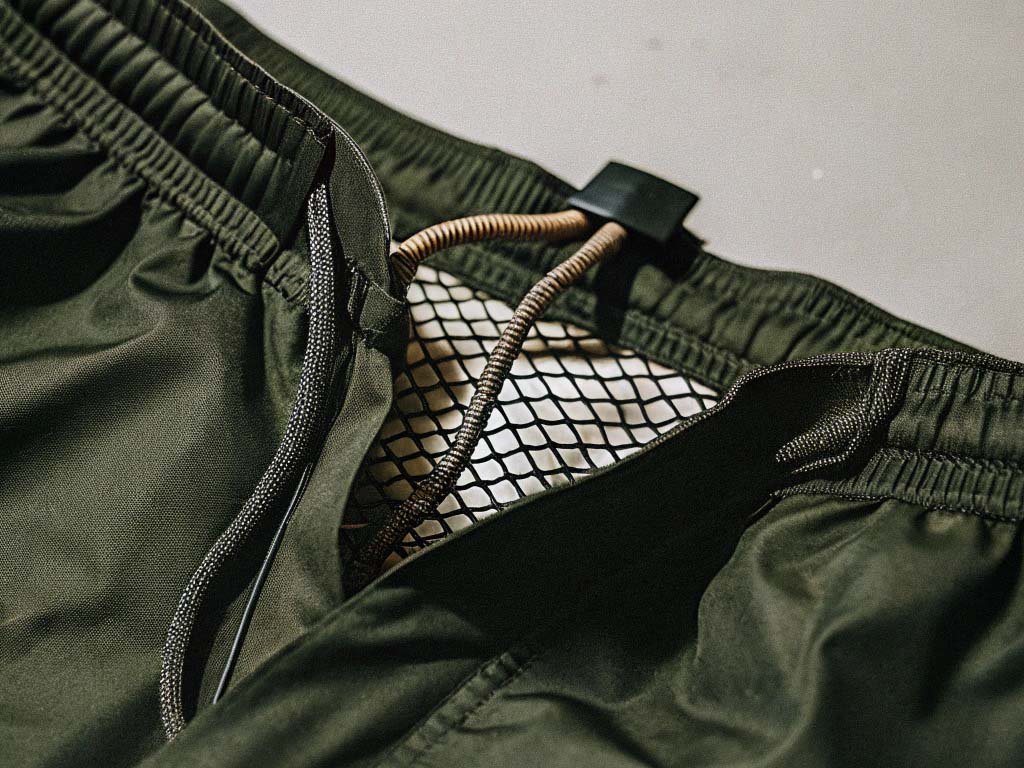 Close-up of green shorts showing drawstring closure, inner mesh lining, and elastic waistband detail.