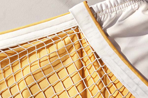 Close-up of yellow shorts with a white mesh lining and elastic waistband, showcasing breathable design.