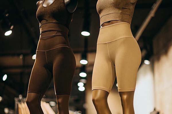 Two mannequins showcasing ribbed biker shorts and crop tops in brown and beige tones under warm store lighting.