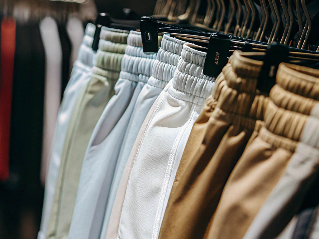 Row of elastic-waist shorts in neutral colors on hangers.