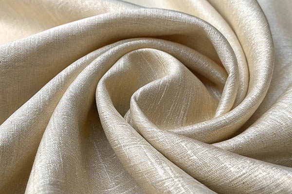 Close-up of soft, shimmering beige fabric elegantly draped in folds.