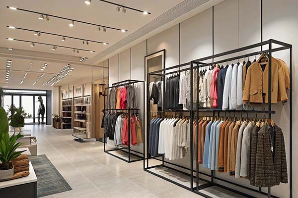 A modern clothing store with neatly arranged garments on racks, bright lighting, and a stylish interior design.