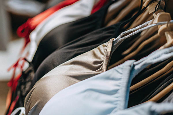 Stylish swimsuits in neutral tones hanging on wooden hangers.