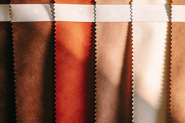 Fabric swatches in warm brown and beige tones with sunlight creating shadows.