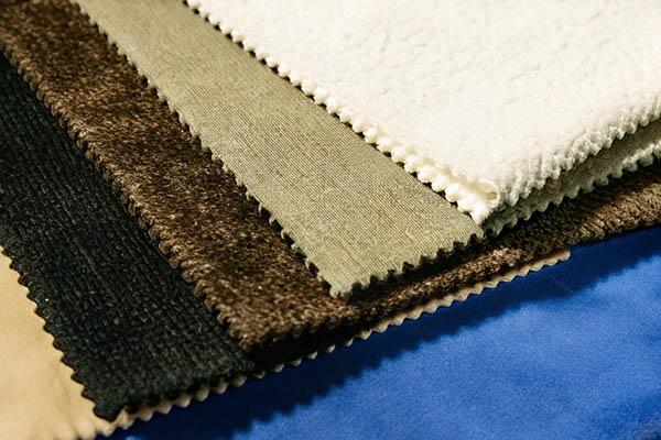 Close-up of fabric swatches in various colors and textures, including cream, brown, green, and blue.