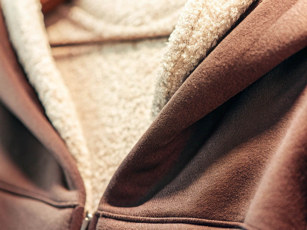 Close-up of a brown hoodie with soft beige fleece lining for warmth and comfort.