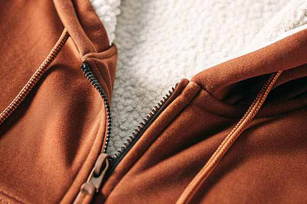 Close-up of a brown zip-up hoodie with white fleece lining and matching drawstrings.