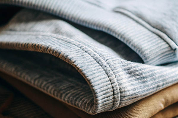 Close-up of folded blue ribbed fabric with visible stitching, stacked on beige material.