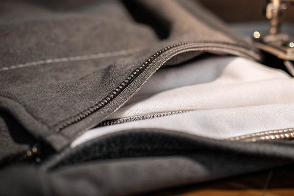 Close-up of a gray hoodie with a partially open zipper, revealing soft white lining.