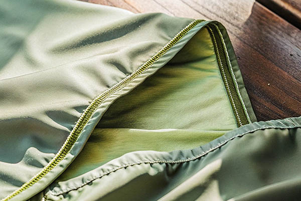 Close-up of green fabric with stitched hem.