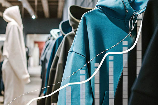 Row of colorful hoodies with a rising bar graph overlay, indicating sales growth trends.