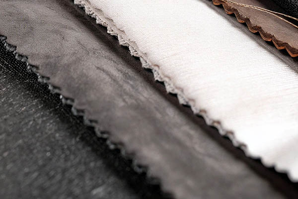 Close-up of black, gray, and white fabric swatches with soft textures and zigzag edges.