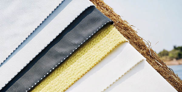 Textured fabric swatches in neutral tones displayed outdoors.