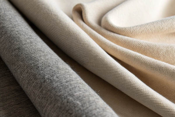 Close-up of gray and beige fabrics with visible weave patterns and soft textures.