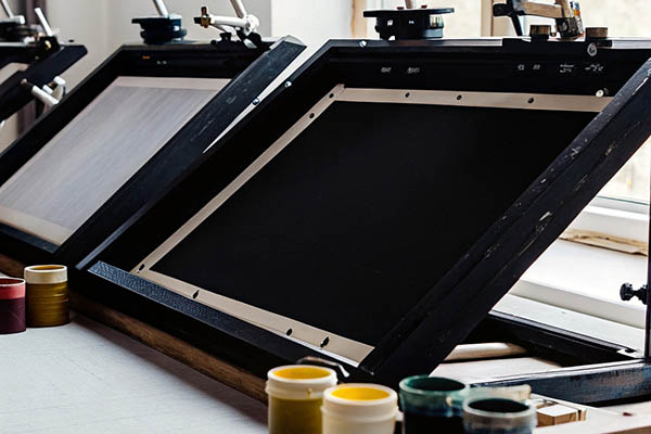 Silkscreen frames and colorful ink pots in a print studio.