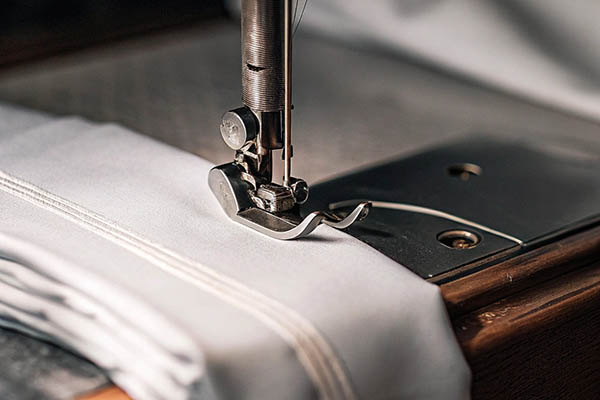 Close-up of a sewing machine needle stitching white fabric with precision.