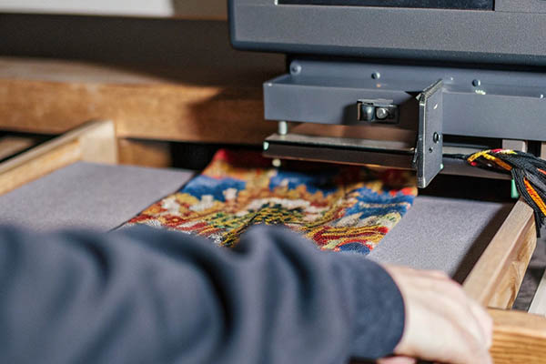 A colorful sock being printed with a detailed design using a specialized textile printer.