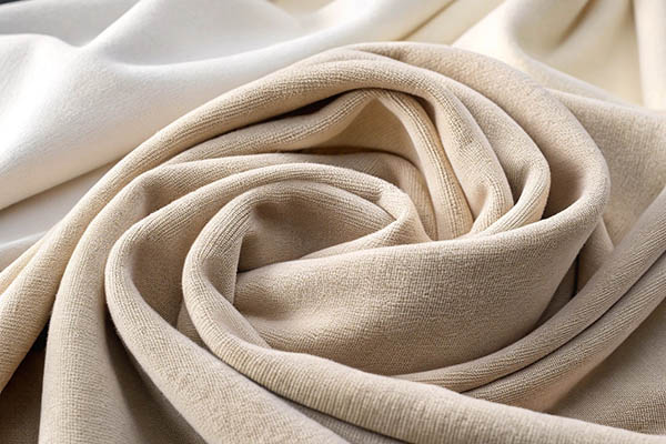 Delicate beige and cream fabrics swirled together, showcasing soft texture and smooth weave.