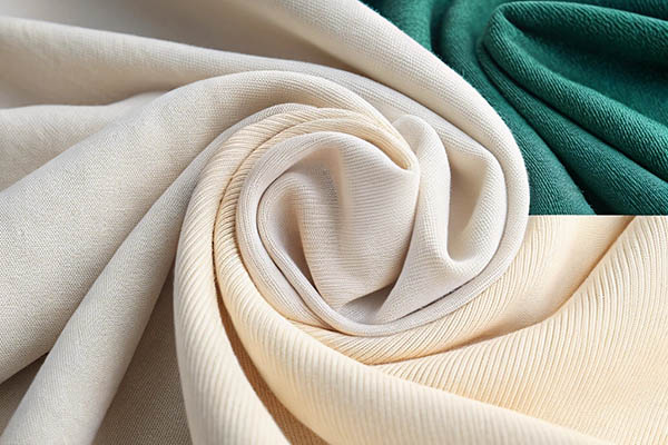 A close-up of cream, beige, and green fabric swirled together, showcasing different textures and materials.