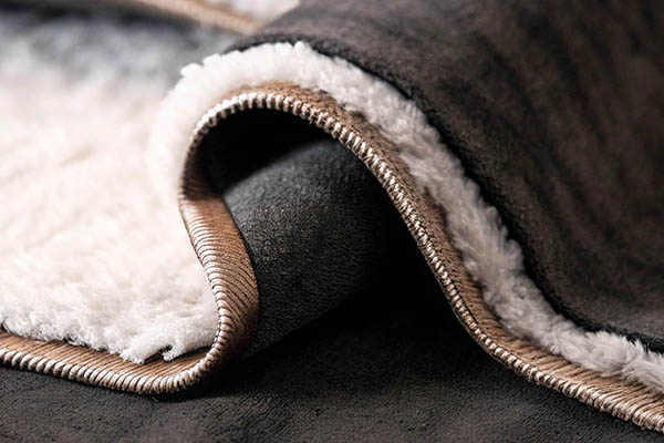 Close-up of white sherpa fleece lining with dark gray suede exterior.