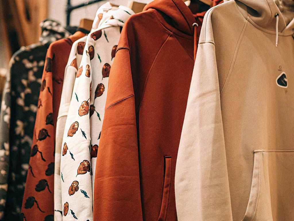 Assorted hoodies in various colors and patterns on clothing rack.