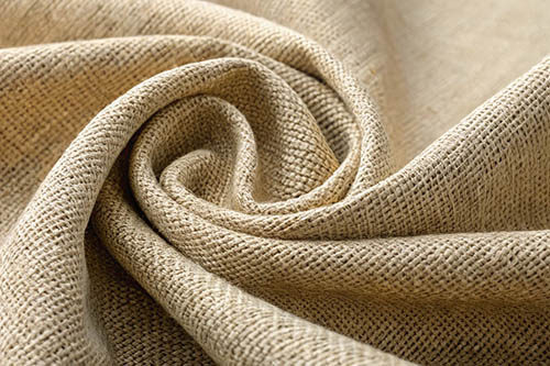 Close-up of beige burlap fabric with a rough woven texture, elegantly folded.