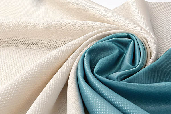 Beige and teal textured fabrics artistically twisted together.