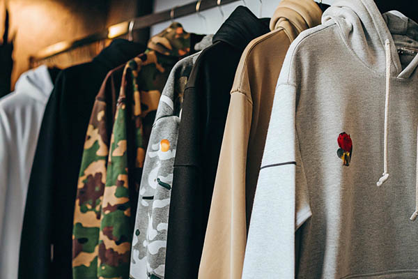 Row of hoodies in camo, beige, and gray with various designs.