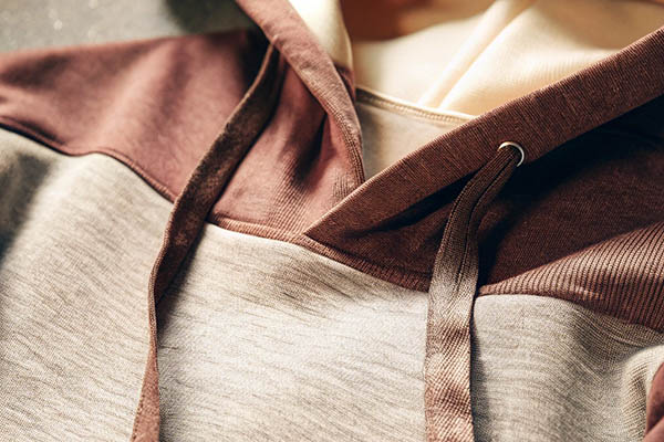Close-up of a two-tone hoodie in brown and beige with matching drawstrings and soft fabric.