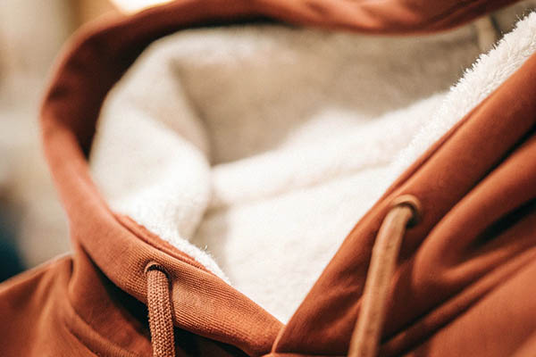 Close-up of a brown hoodie with soft white fleece lining for warmth.