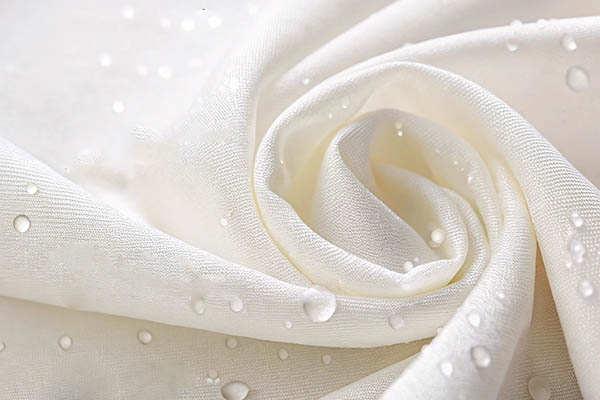 White fabric with water droplets showcasing hydrophobic properties.