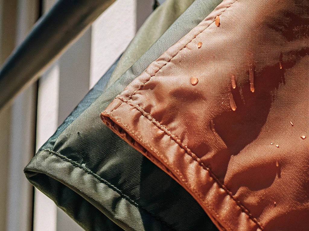 Close-up of water droplets on orange and green shorts hanging to dry.