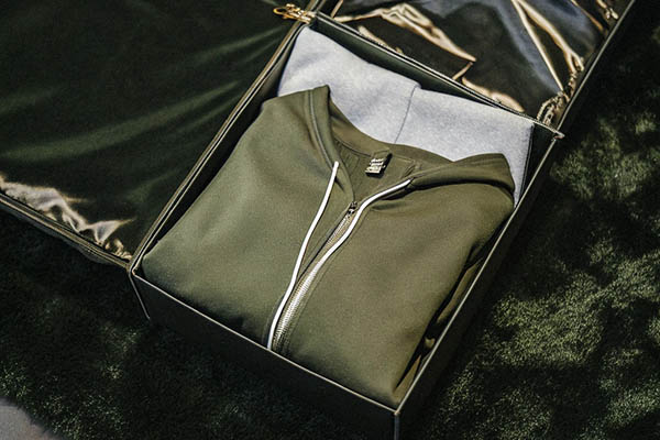 Folded green zip-up hoodie in a sleek black gift box.