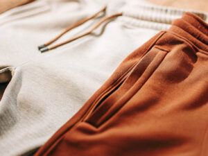 Close-up of beige and brown sweatpants with drawstrings and zippered pockets.