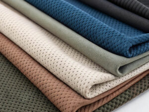 Neatly stacked perforated mesh fabrics in earthy and navy tones.