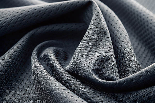Close-up of dark gray perforated mesh fabric, showcasing its breathable and flexible texture.
