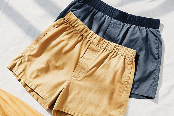 Beige and navy blue cotton shorts laid on a white fabric background.