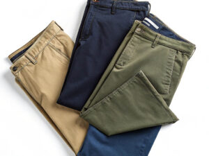 Three pairs of neatly folded chino pants in khaki, navy blue, and olive green.